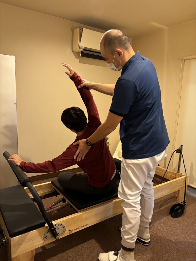 ピラティスを受けている女性と指導しているスタッフ